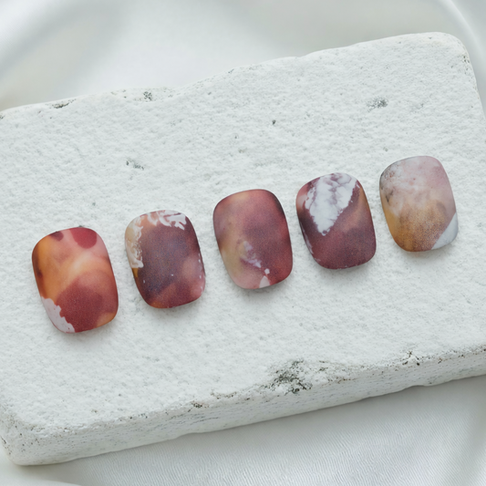 Earthy abstract press-on nails in matte brown and orange tones.