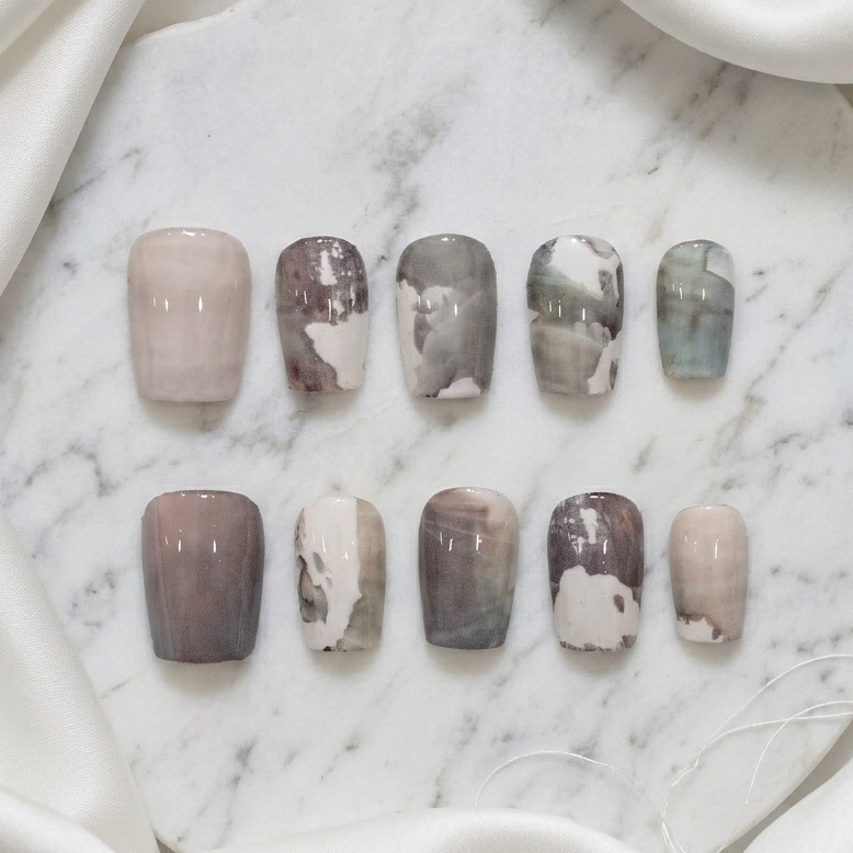 A full set of ten press-on nails featuring various monochrome gray, white, and brown artistic abstract designs.