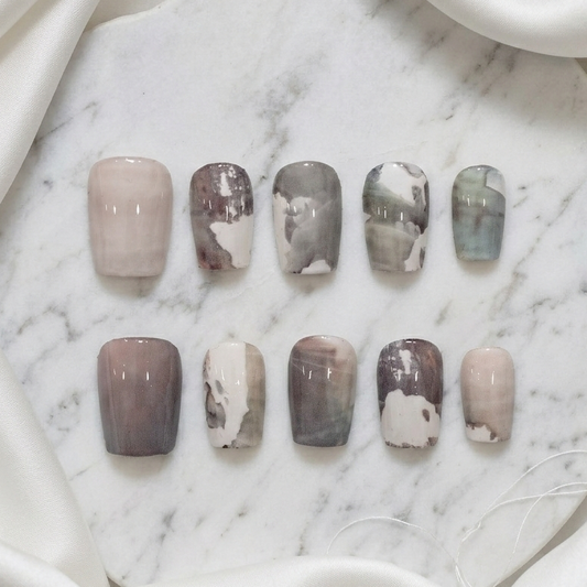 A full set of ten press-on nails featuring various monochrome gray, white, and brown artistic abstract designs.