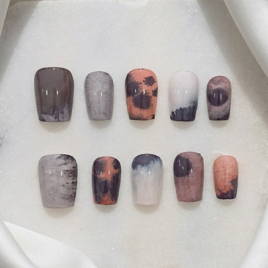 Abstract, splotchy, and organic painterly press-on nail set in warm earth tones like brown, cream, and burnt orange.