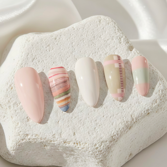 A set of almond-shaped press-on nails featuring soft pastel colors, plaid patterns, and solid cream accents.