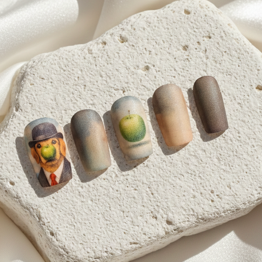 Hand-painted press-on nails featuring a dog wearing a bowler hat, inspired by Magritte's surrealist art on a stone display.