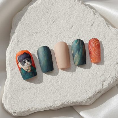 A set of press-on nails with an artistic cat portrait and complementary dark green and terracotta abstract designs.
